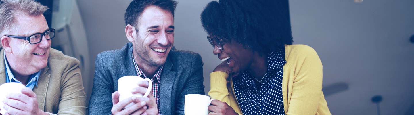 three people laughing over coffee.