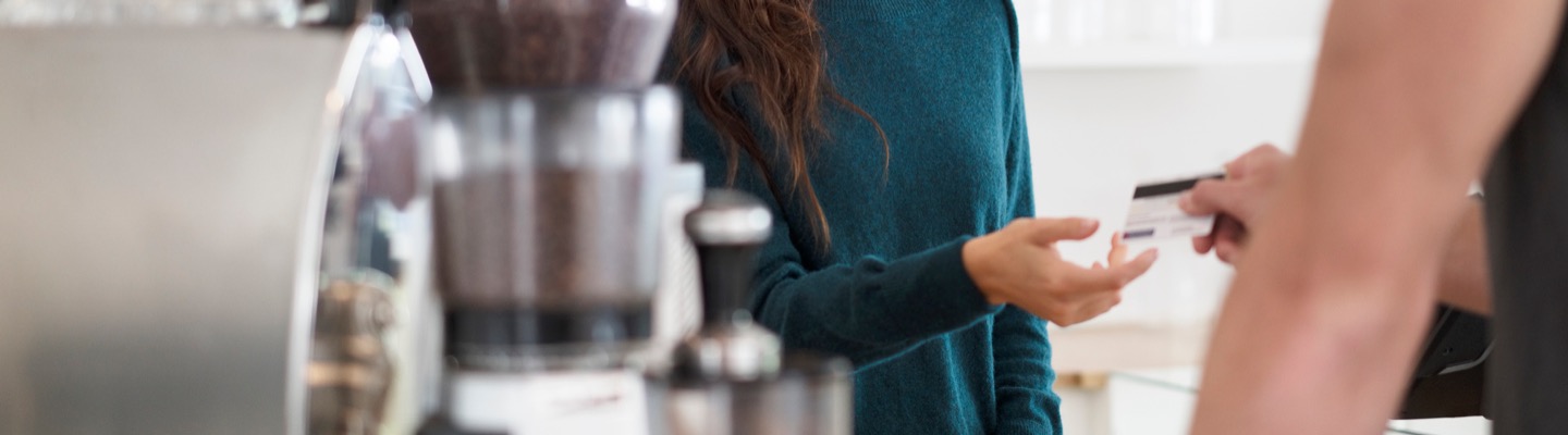 A person handing barista a card for payment