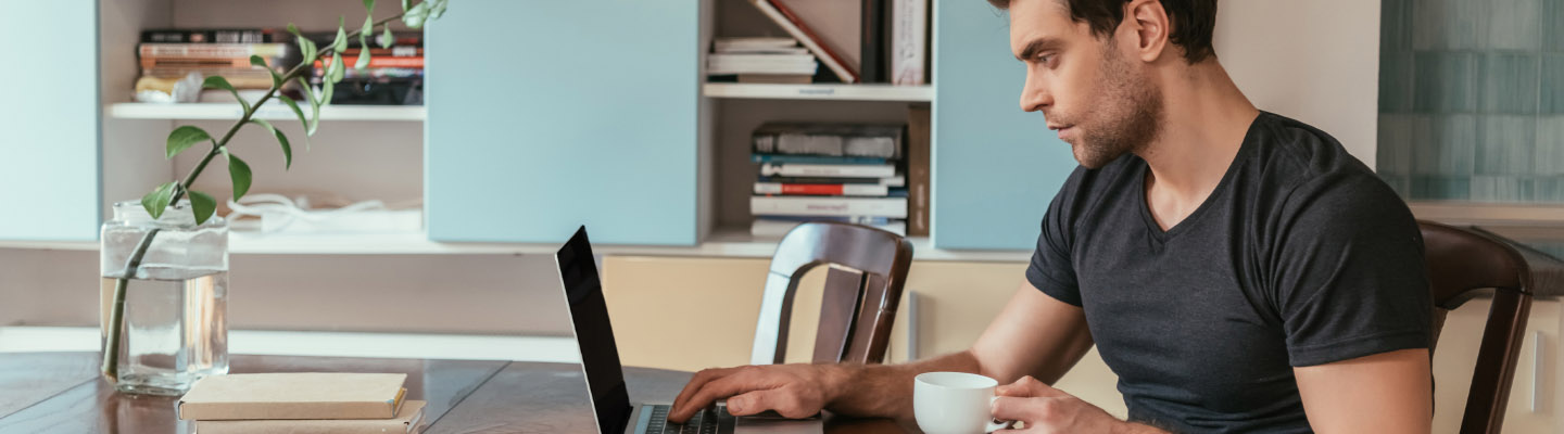 man looking at laptop with coffee